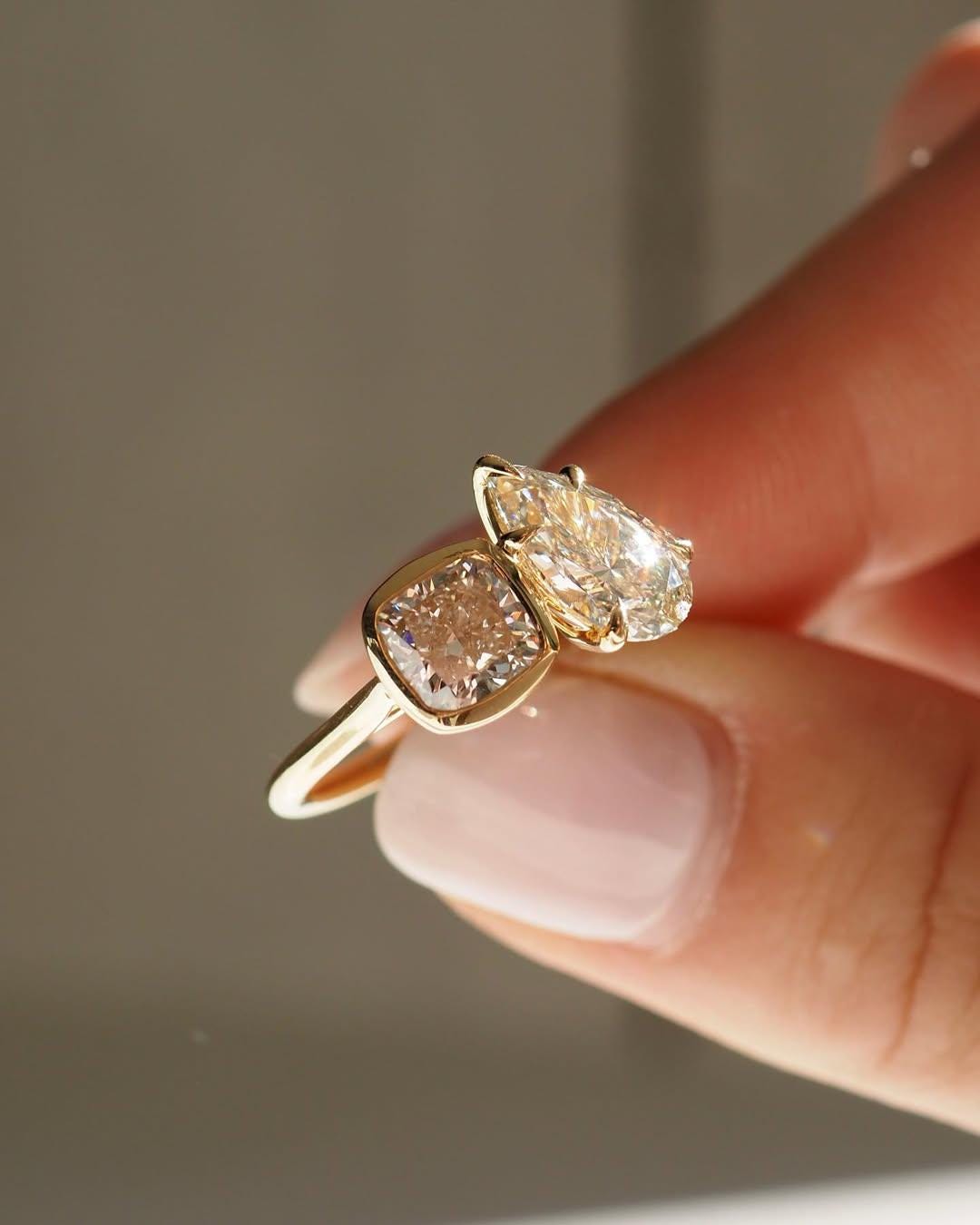 Toi et Moi Bezel Set ring design features two lab-grown diamonds, 1.85-carat pear-shaped diamond and 1.65-carat square cushion-cut diamond