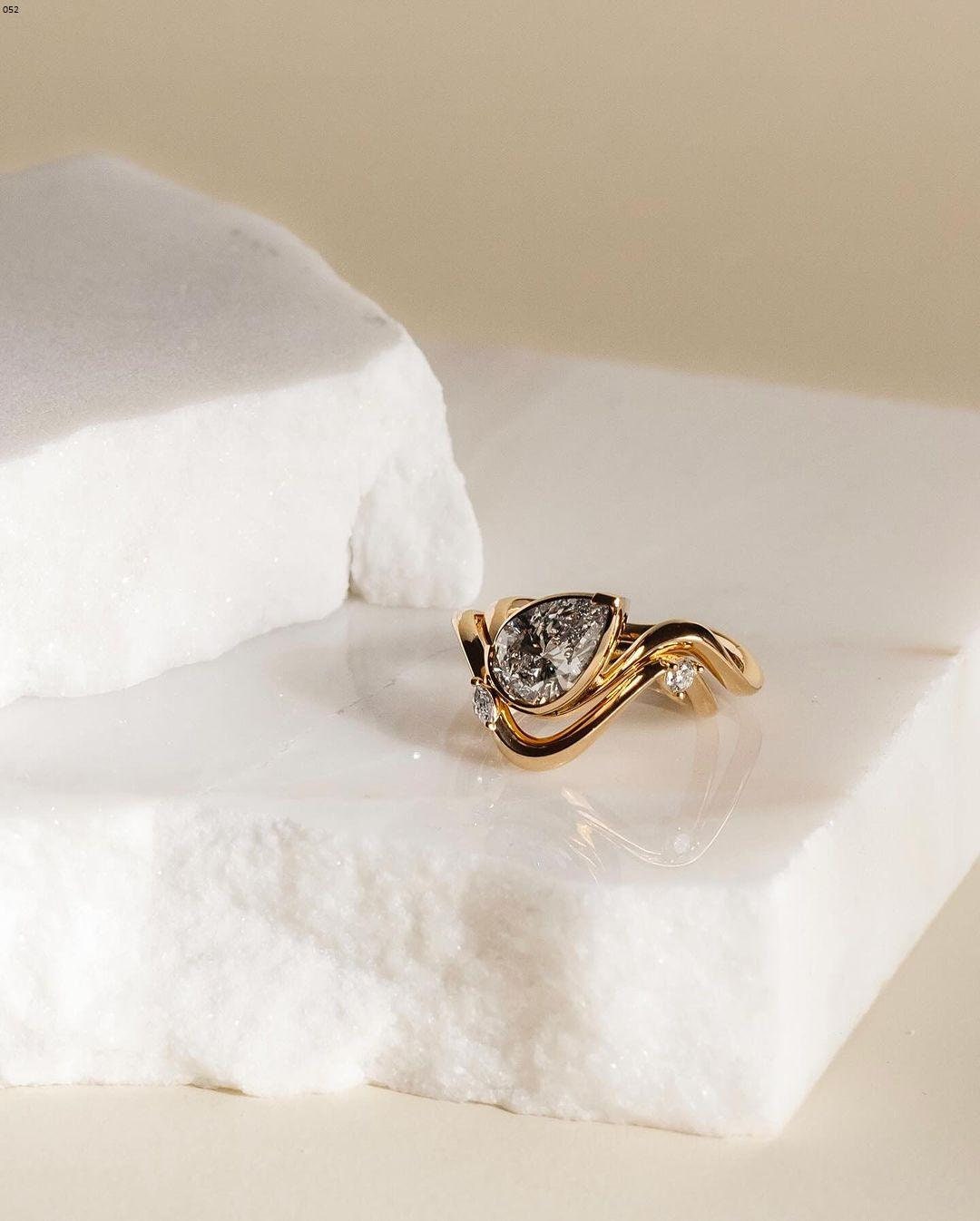 1.50 CT Pear cut diamond, low-set in a semi bezel along a sweeping wave of 18k yellow gold.Made to pair with our Laraine wedding ring